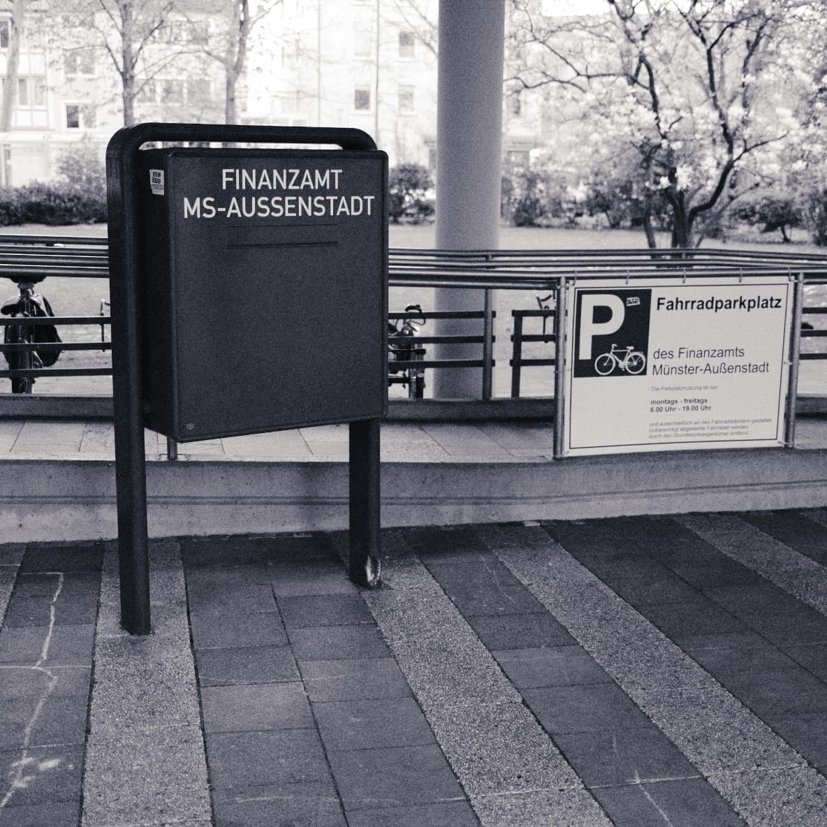 Amtlicher Briefkasten mit der Aufschrift „Finanzamt MS-Außenstadt“ neben einem Fahrradparkplatz-Schild.