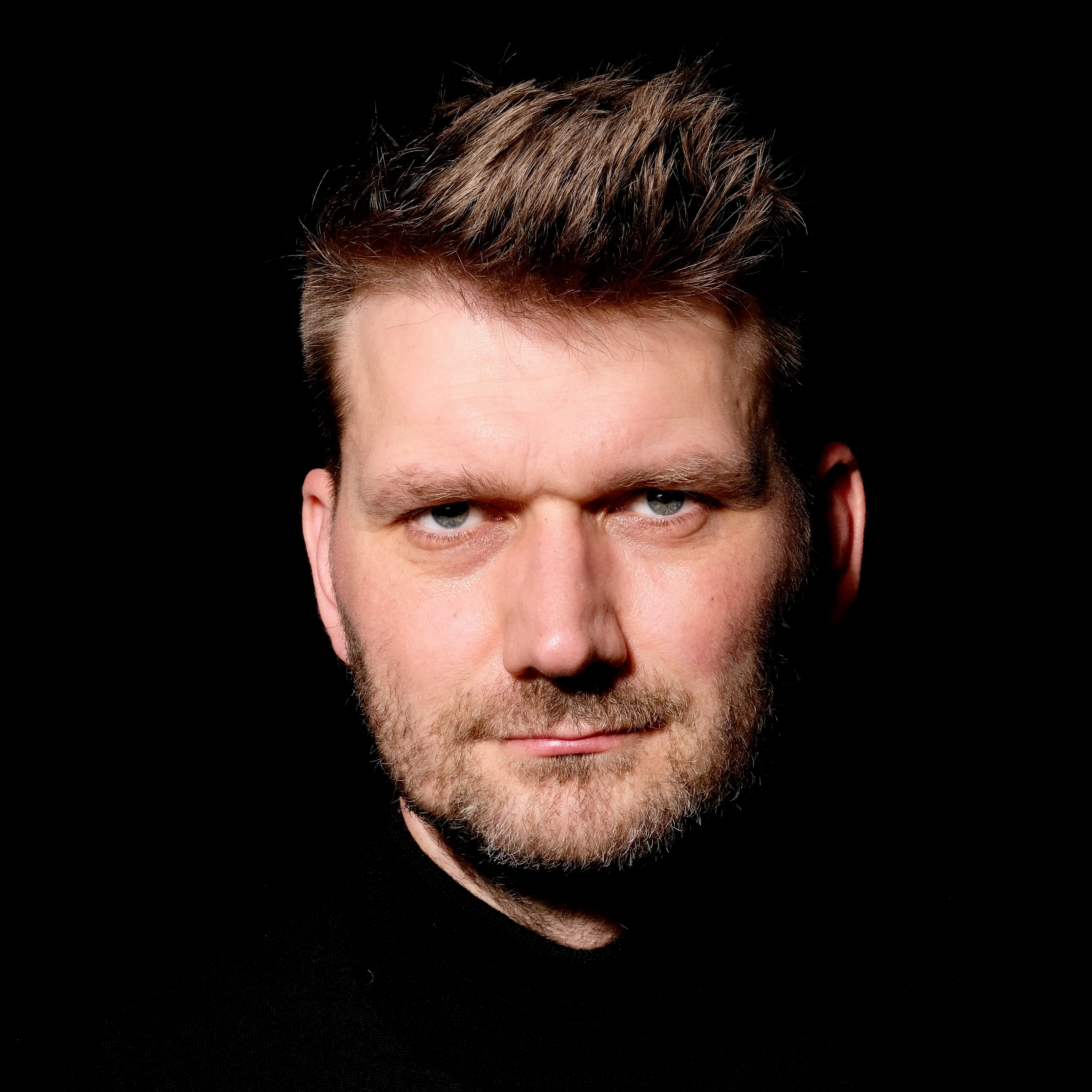 Hendrik Bruns, nahes Farbporträt vor schwarzem Grund.