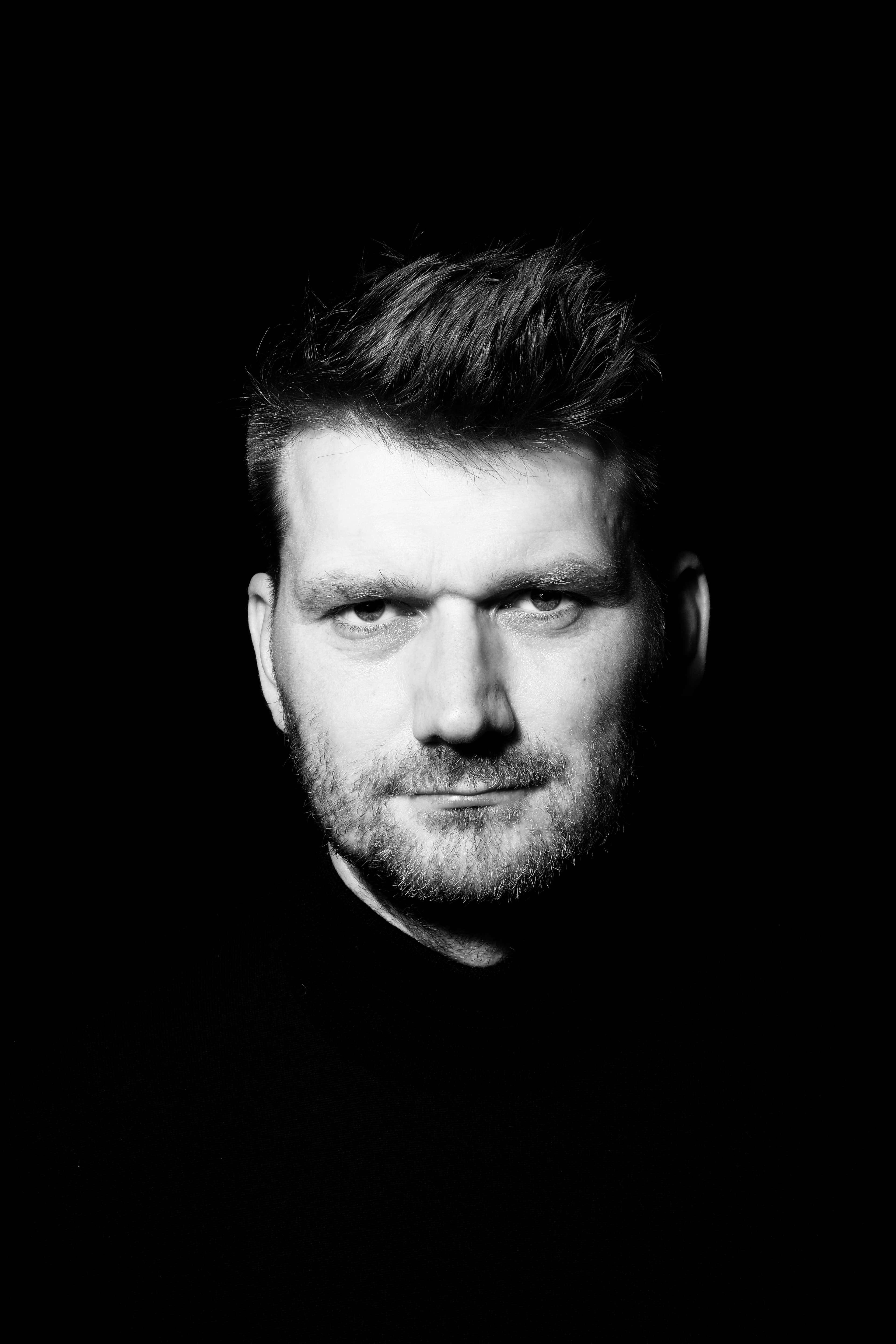 Hendrik Bruns, Schwarz-Weiß-Porträt vor schwarzem Grund, Blick in die Kamera.